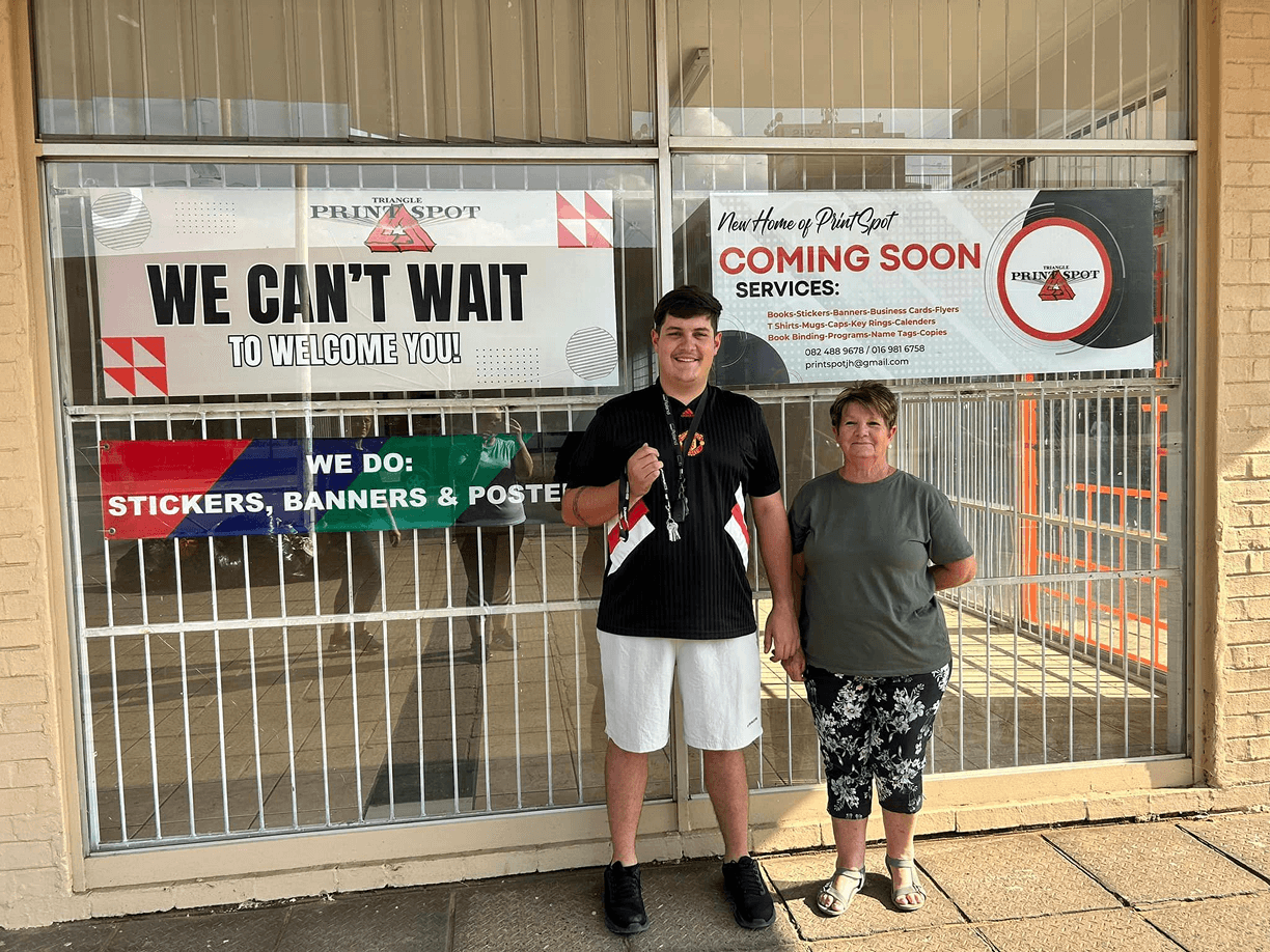 A photo of the owners of Triangle Print Spot in front of their new store location.